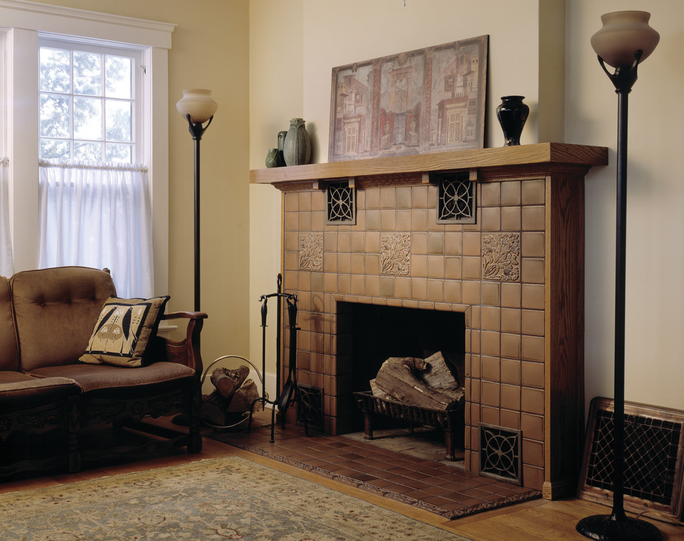 Aménagement d'une salle de séjour craftsman avec un mur jaune, un sol en bois brun, une cheminée standard, un manteau de cheminée en carrelage et un sol marron.