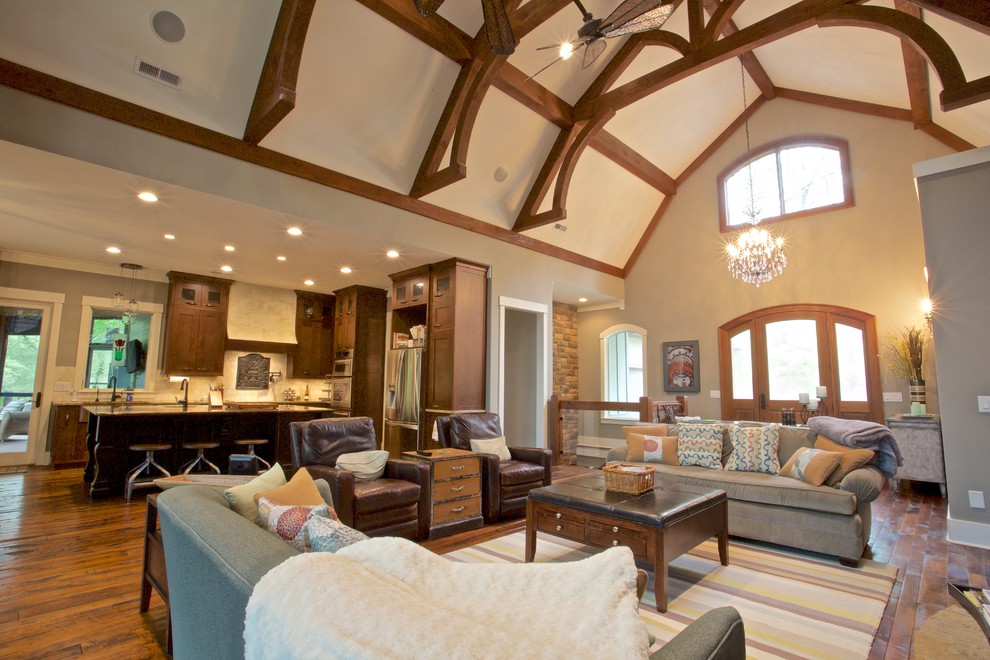 Großes, Offenes Klassisches Wohnzimmer mit Hausbar, beiger Wandfarbe, braunem Holzboden, Kamin, Kaminumrandung aus Stein und TV-Wand