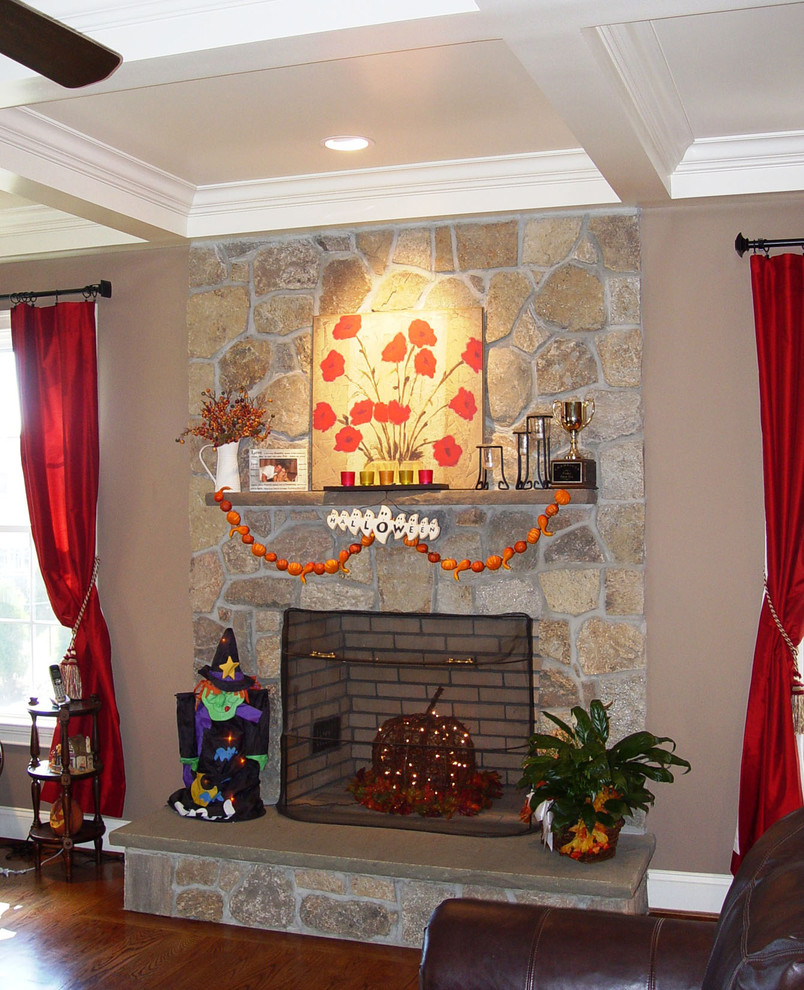 Diseño de sala de estar abierta de estilo americano grande con paredes beige, todas las chimeneas, marco de chimenea de piedra, televisor independiente, suelo de madera en tonos medios y suelo marrón