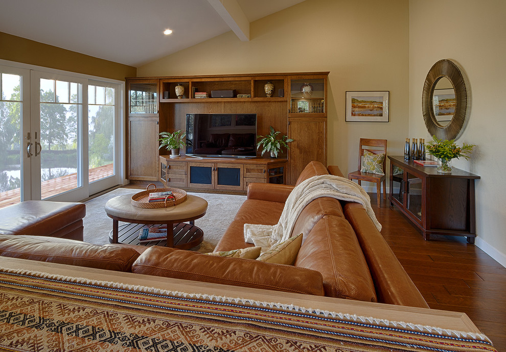 Cette image montre une salle de séjour craftsman de taille moyenne et ouverte avec un mur beige, parquet foncé, aucune cheminée et un téléviseur encastré.