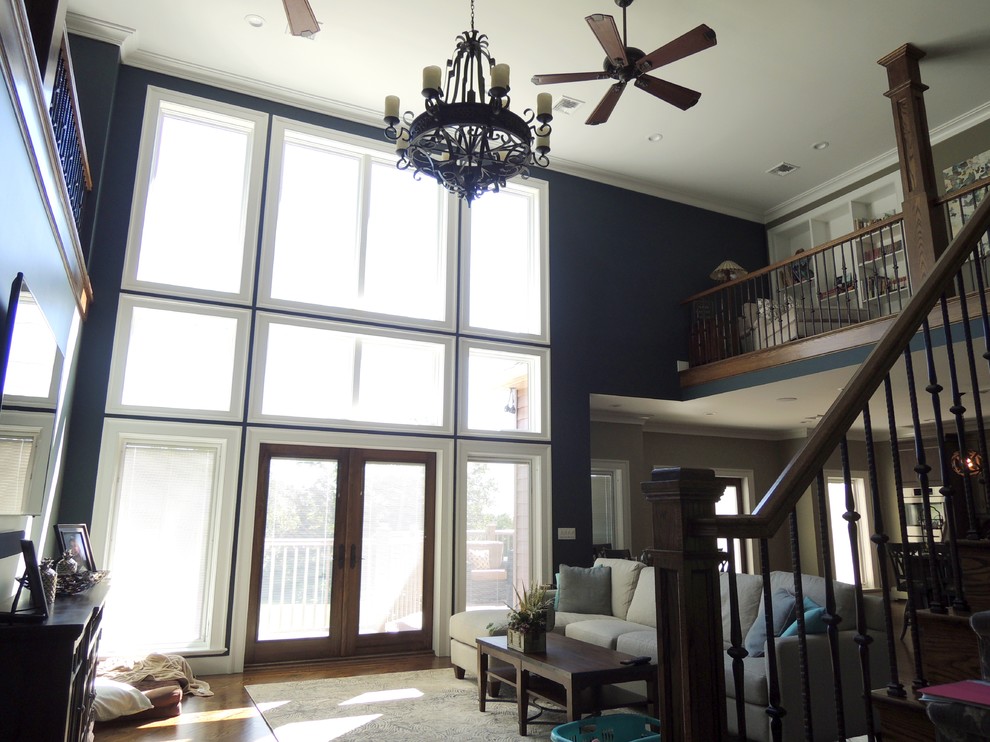 Example of a large arts and crafts open concept dark wood floor and brown floor family room design in New York with blue walls, no fireplace and a wall-mounted tv