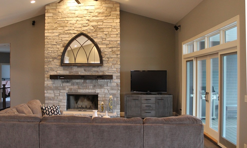 Пример оригинального дизайна: открытая гостиная комната среднего размера в стиле кантри с стандартным камином, фасадом камина из камня, бежевыми стенами, паркетным полом среднего тона и телевизором в углу