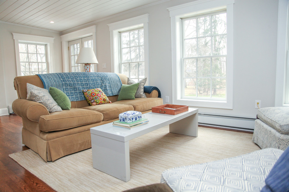 Foto de sala de estar cerrada campestre pequeña sin chimenea con paredes blancas, suelo de madera en tonos medios y televisor colgado en la pared