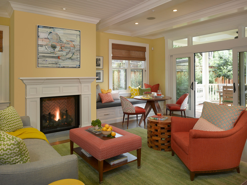 Пример оригинального дизайна: гостиная комната в стиле неоклассика (современная классика) с желтыми стенами, светлым паркетным полом, стандартным камином и фасадом камина из дерева