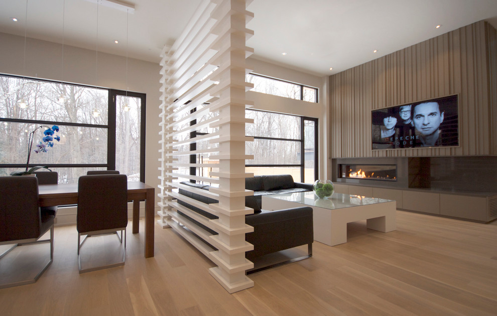 Ejemplo de sala de estar abierta contemporánea grande con paredes blancas, suelo de madera clara, chimenea lineal, marco de chimenea de piedra y pared multimedia