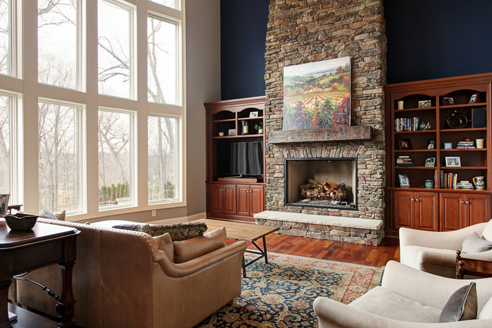 コロンバスにあるラグジュアリーな広いトランジショナルスタイルのおしゃれなオープンリビング (青い壁、濃色無垢フローリング、標準型暖炉、石材の暖炉まわり、埋込式メディアウォール、茶色い床) の写真