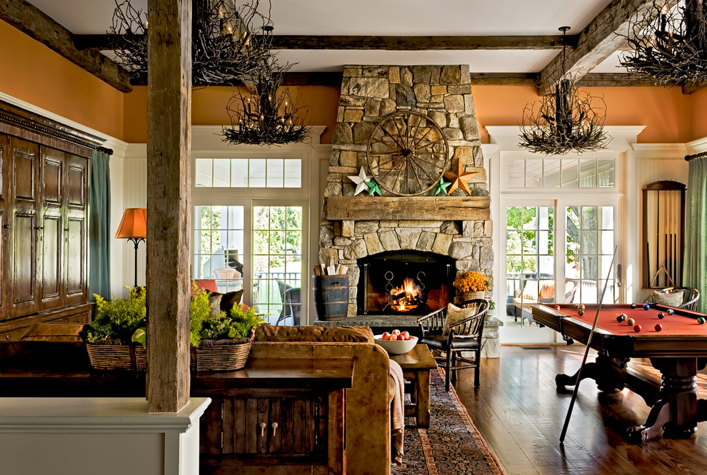 Imagen de sala de estar tradicional con parades naranjas y marco de chimenea de piedra