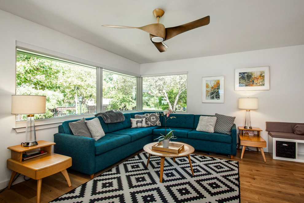 Foto de sala de estar abierta de tamaño medio sin chimenea con paredes blancas, suelo de madera en tonos medios, televisor independiente y suelo marrón