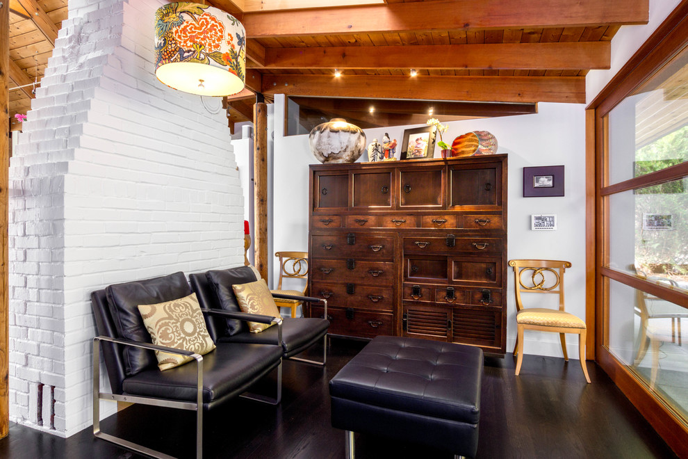 Cette photo montre une petite salle de séjour tendance ouverte avec un mur blanc, parquet foncé, une cheminée standard, un sol noir et un manteau de cheminée en brique.