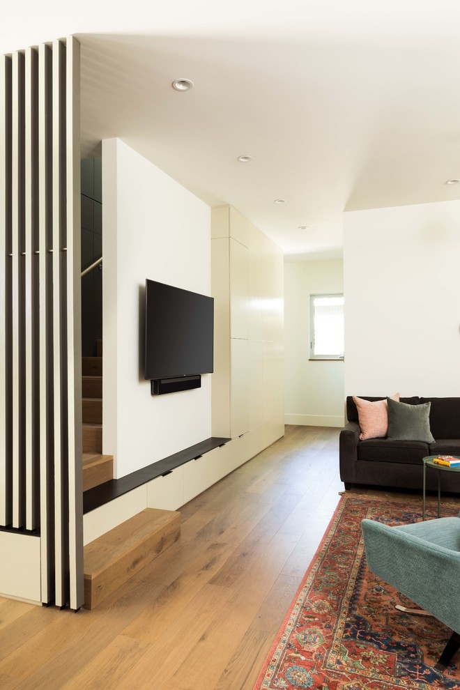 Esempio di un grande soggiorno tradizionale chiuso con pareti bianche, pavimento in legno massello medio, nessun camino, TV a parete e pavimento marrone