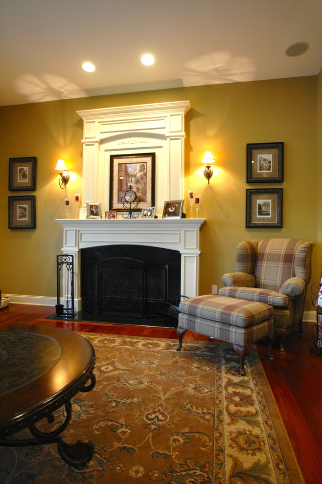 Example of a classic dark wood floor family room design in Chicago with yellow walls, a standard fireplace and a wood fireplace surround