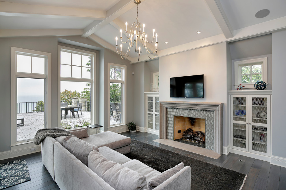 Идея дизайна: гостиная комната в стиле неоклассика (современная классика) с серыми стенами, паркетным полом среднего тона, стандартным камином, фасадом камина из камня, телевизором на стене и ковром на полу