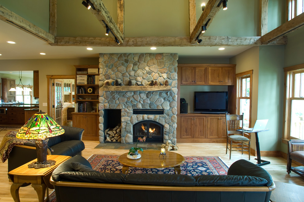 Idée de décoration pour une salle de séjour craftsman ouverte avec un mur vert, parquet clair, un manteau de cheminée en pierre et un téléviseur encastré.