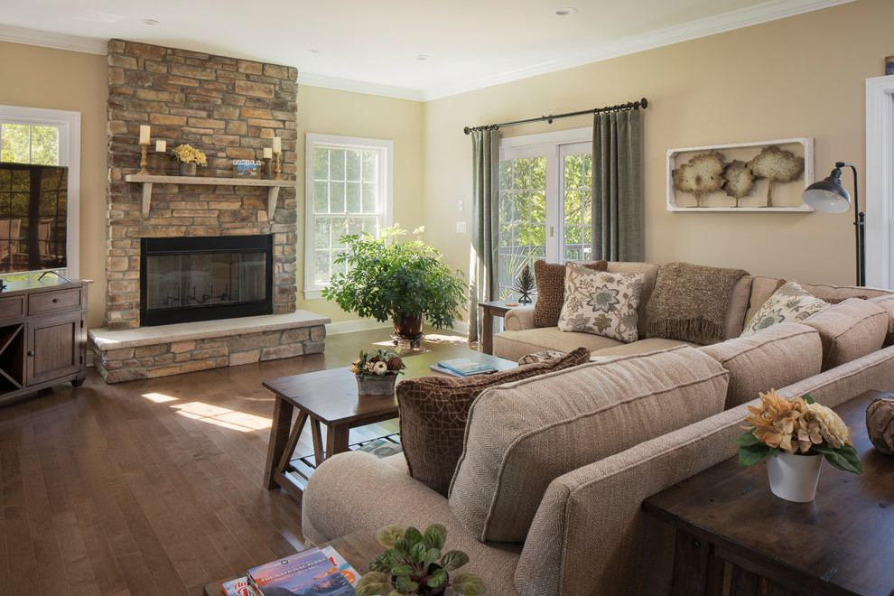 Cette image montre une grande salle de séjour traditionnelle ouverte avec un sol en bois brun, une cheminée standard, un manteau de cheminée en pierre et un téléviseur indépendant.