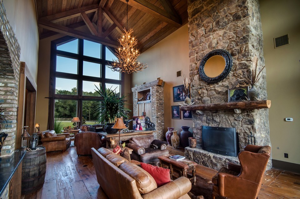 Ejemplo de sala de estar rural grande con marco de chimenea de piedra