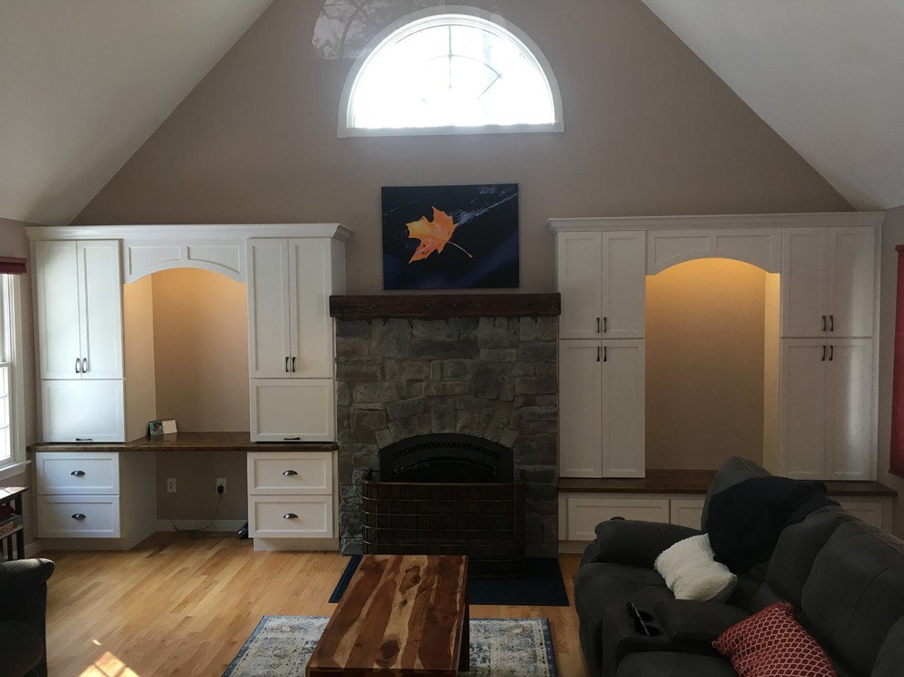 Modelo de sala de estar abierta clásica renovada grande sin televisor con paredes beige, suelo de madera clara, todas las chimeneas, marco de chimenea de piedra y suelo beige