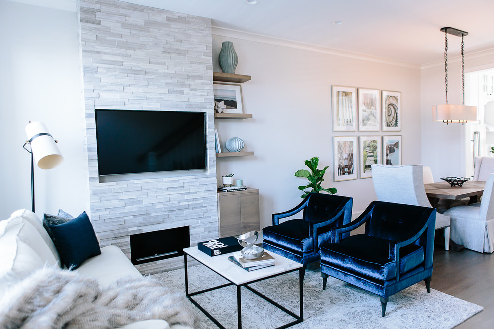 Источник вдохновения для домашнего уюта: открытая гостиная комната среднего размера в современном стиле с серыми стенами, паркетным полом среднего тона, стандартным камином, фасадом камина из камня, телевизором на стене, коричневым полом и ковром на полу