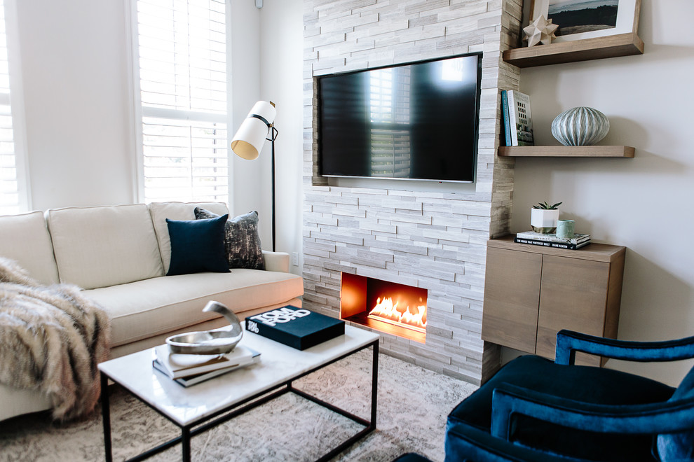 Ejemplo de sala de estar abierta contemporánea de tamaño medio con paredes grises, suelo de madera en tonos medios, todas las chimeneas, marco de chimenea de piedra, televisor colgado en la pared y suelo marrón