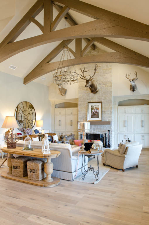 Geräumiges, Offenes Klassisches Wohnzimmer mit beiger Wandfarbe, hellem Holzboden, Kamin und Kaminumrandung aus Stein in Austin
