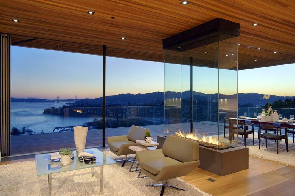 Expansive contemporary open plan games room in San Francisco with beige walls, limestone flooring, a two-sided fireplace and a stone fireplace surround.