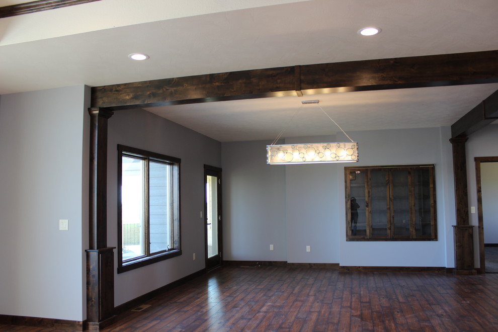 Diseño de sala de estar abierta rural de tamaño medio sin televisor con suelo de madera oscura, chimenea de esquina y marco de chimenea de madera