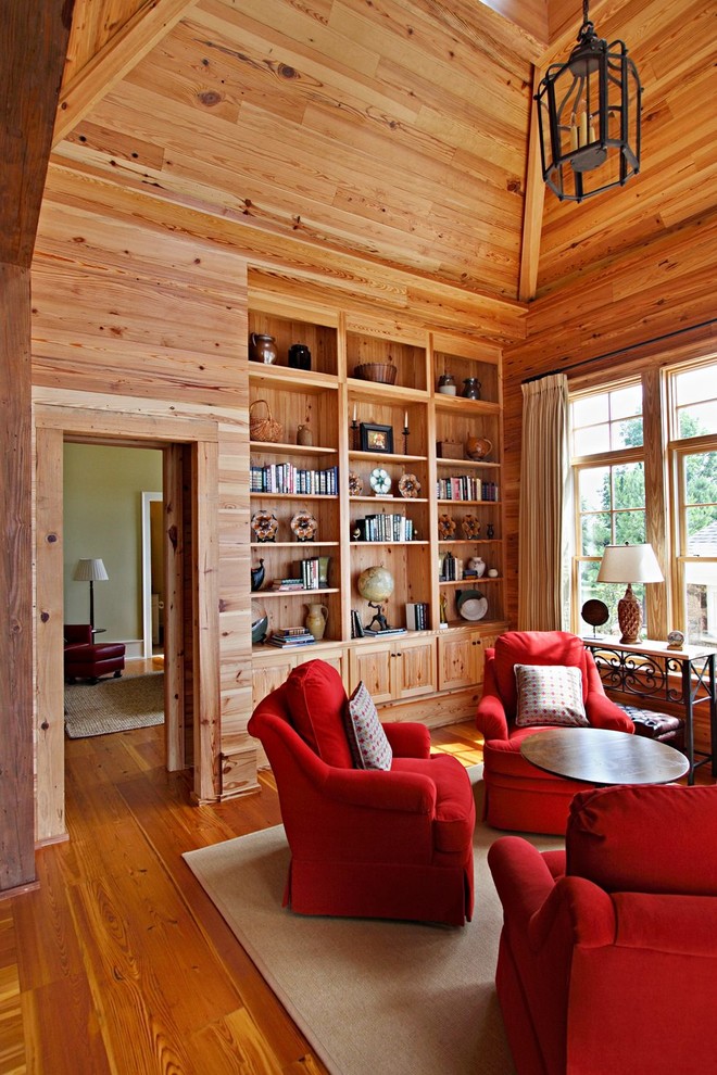 Esempio di un soggiorno chic con libreria, pavimento in legno massello medio e tappeto