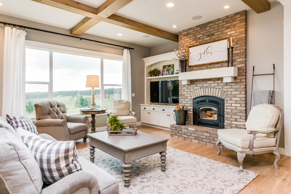 Inspiration for a medium sized farmhouse open plan games room in Denver with grey walls, light hardwood flooring, a standard fireplace, a brick fireplace surround, a freestanding tv and brown floors.