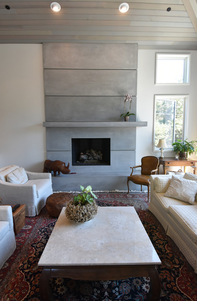 Aménagement d'une grande salle de séjour campagne ouverte avec un mur gris, un sol en bois brun, un manteau de cheminée en béton et un téléviseur indépendant.