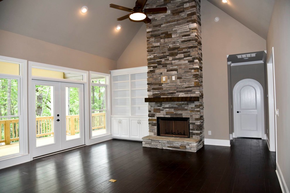 Идея дизайна: изолированная гостиная комната среднего размера в стиле кантри с серыми стенами, темным паркетным полом, стандартным камином, фасадом камина из камня и коричневым полом