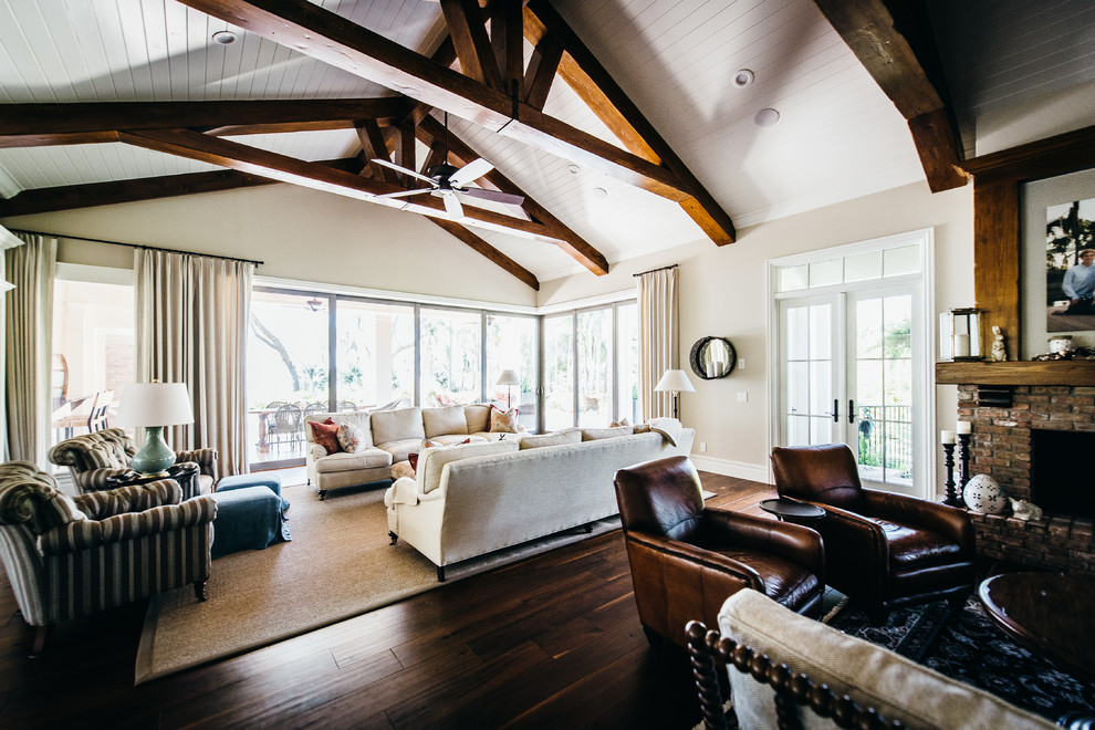 Diseño de sala de estar abierta clásica renovada grande con paredes beige, suelo de madera oscura y televisor retractable