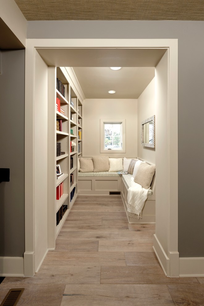 Foto di un soggiorno chic con libreria, pareti beige, parquet chiaro e pavimento beige