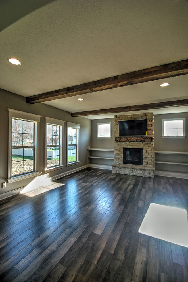 Foto de sala de estar abierta tradicional de tamaño medio con suelo de madera oscura, marco de chimenea de piedra y televisor colgado en la pared