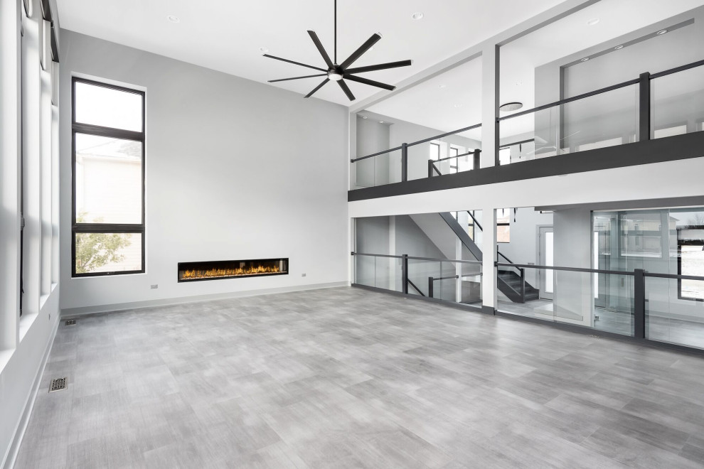 Réalisation d'une très grande salle de séjour minimaliste ouverte avec un mur gris, une cheminée ribbon, un sol gris et un plafond voûté.