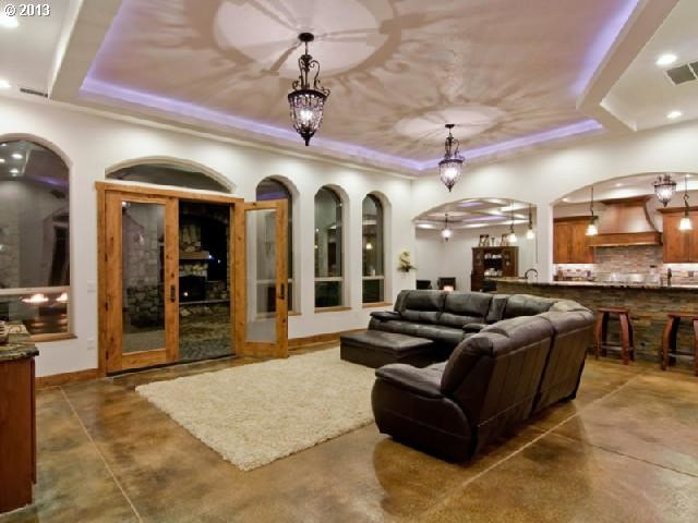 Imagen de sala de estar abierta mediterránea grande sin chimenea con paredes blancas, suelo de cemento y suelo marrón