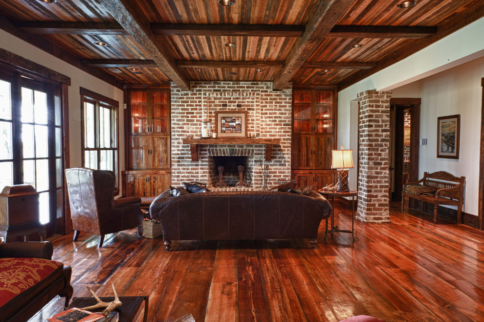 Mid-sized elegant open concept medium tone wood floor and brown floor family room photo in Charleston with white walls, a standard fireplace, a brick fireplace and no tv