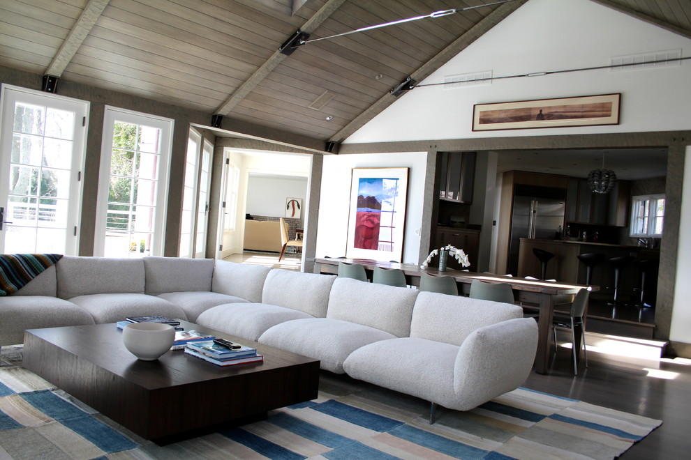 Diseño de sala de estar abierta contemporánea grande con paredes blancas, suelo de madera en tonos medios, todas las chimeneas, marco de chimenea de piedra y televisor colgado en la pared
