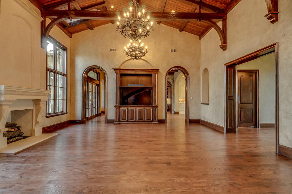 Großes, Offenes Mediterranes Wohnzimmer mit beiger Wandfarbe, braunem Holzboden, Kamin und Kaminumrandung aus Stein in Dallas