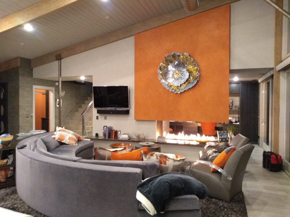 Свежая идея для дизайна: большая открытая гостиная комната в современном стиле с оранжевыми стенами, полом из керамической плитки, угловым камином, фасадом камина из камня, телевизором на стене, серым полом, сводчатым потолком и панелями на части стены - отличное фото интерьера