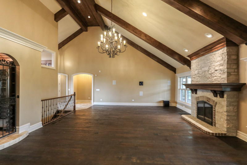 This is an example of a rustic open plan games room in Chicago with beige walls, dark hardwood flooring, a standard fireplace, a stone fireplace surround, a built-in media unit and brown floors.