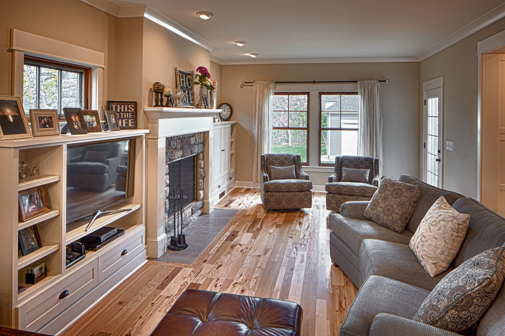 Imagen de sala de estar abierta de estilo americano de tamaño medio con paredes beige, todas las chimeneas, marco de chimenea de piedra y televisor independiente