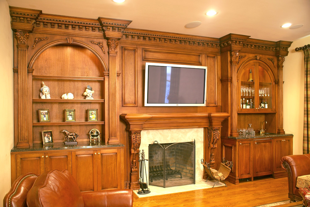 На фото: большая открытая гостиная комната в классическом стиле с с книжными шкафами и полками, бежевыми стенами, полом из ламината, стандартным камином, фасадом камина из дерева, телевизором на стене и желтым полом