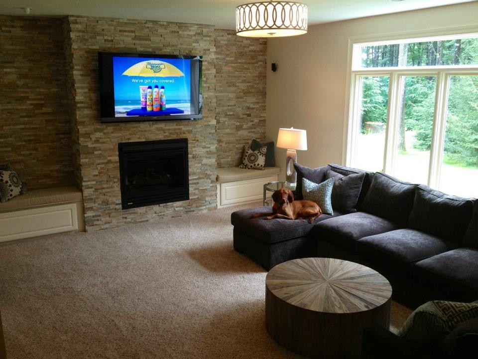 На фото: изолированная гостиная комната среднего размера в стиле модернизм с бежевыми стенами, ковровым покрытием, стандартным камином, фасадом камина из камня и телевизором на стене