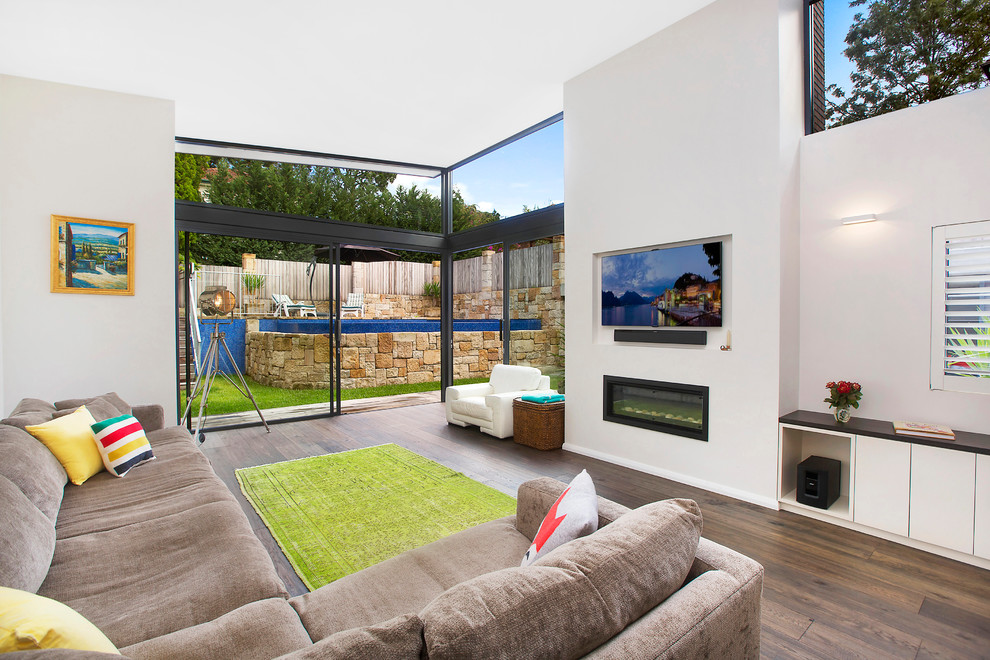 Mittelgroßes, Offenes Modernes Wohnzimmer mit weißer Wandfarbe, dunklem Holzboden, Gaskamin, verputzter Kaminumrandung und TV-Wand in Sydney