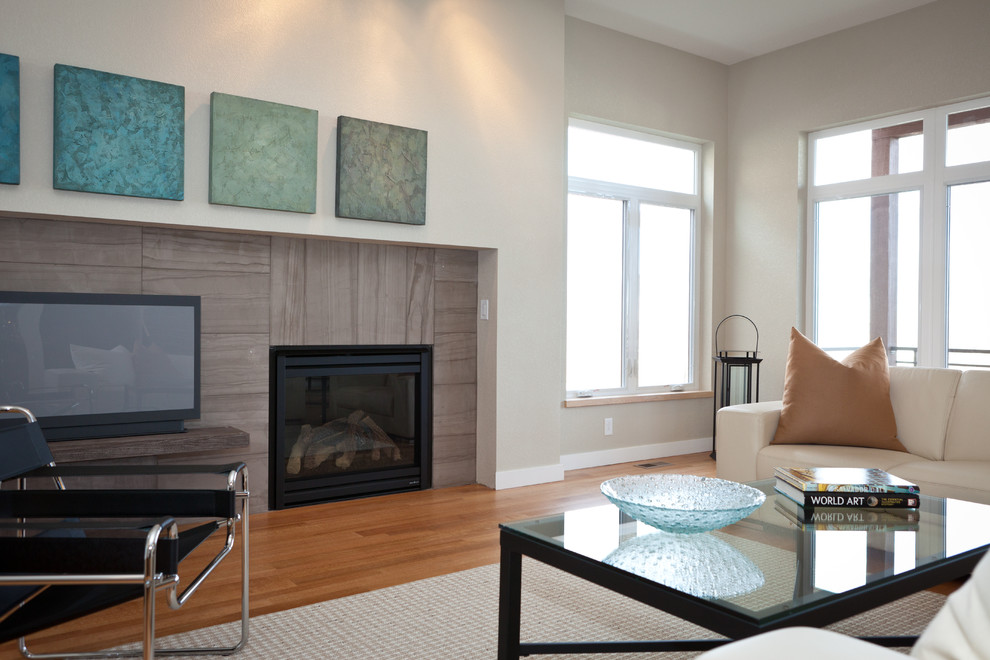 Mittelgroßes, Offenes Modernes Wohnzimmer mit beiger Wandfarbe, braunem Holzboden, Kamin, gefliester Kaminumrandung, freistehendem TV und braunem Boden in Denver