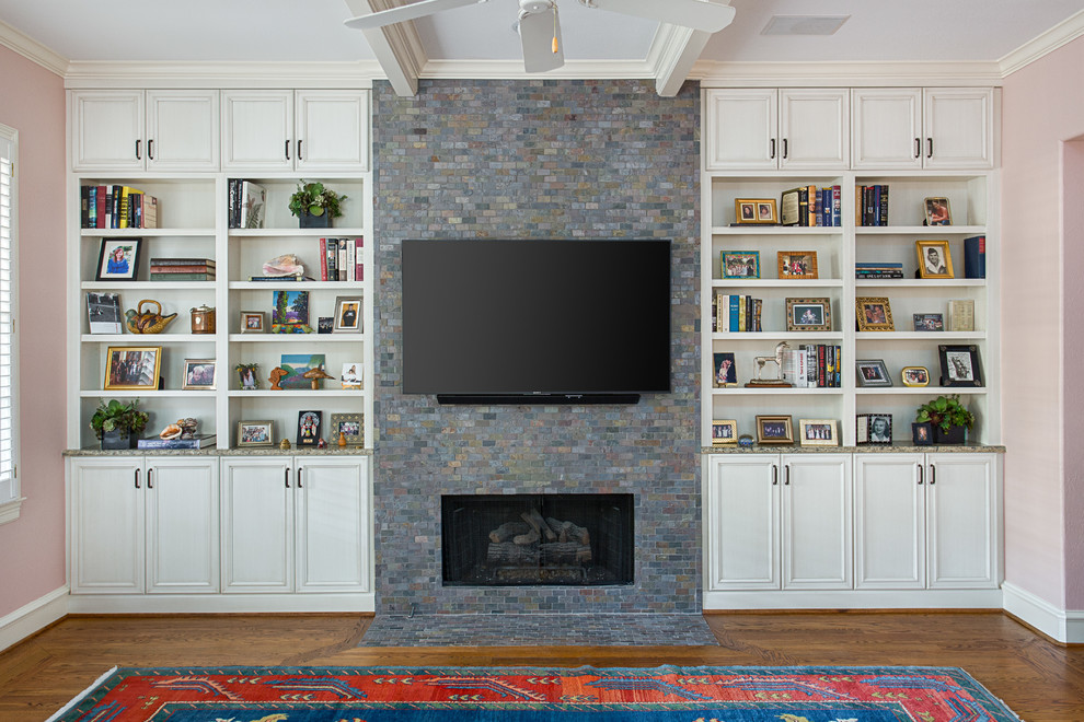 Foto de sala de estar de estilo americano con paredes rosas, suelo de madera en tonos medios, todas las chimeneas, marco de chimenea de piedra, televisor colgado en la pared y suelo marrón