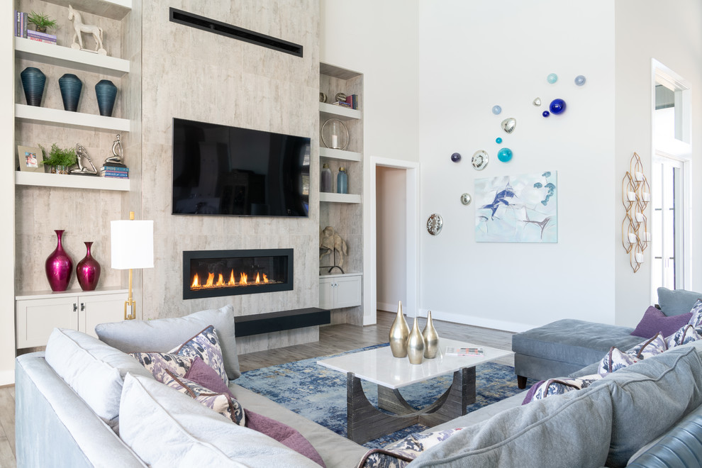 Großes, Offenes Modernes Wohnzimmer mit braunem Holzboden, Gaskamin, gefliester Kaminumrandung, TV-Wand, grauem Boden und grauer Wandfarbe in Austin