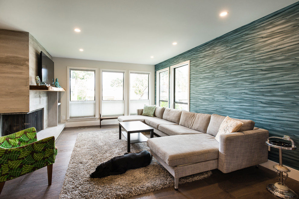 Modelo de sala de estar abierta contemporánea de tamaño medio con paredes grises, suelo de madera en tonos medios, chimenea de esquina, marco de chimenea de hormigón y televisor colgado en la pared