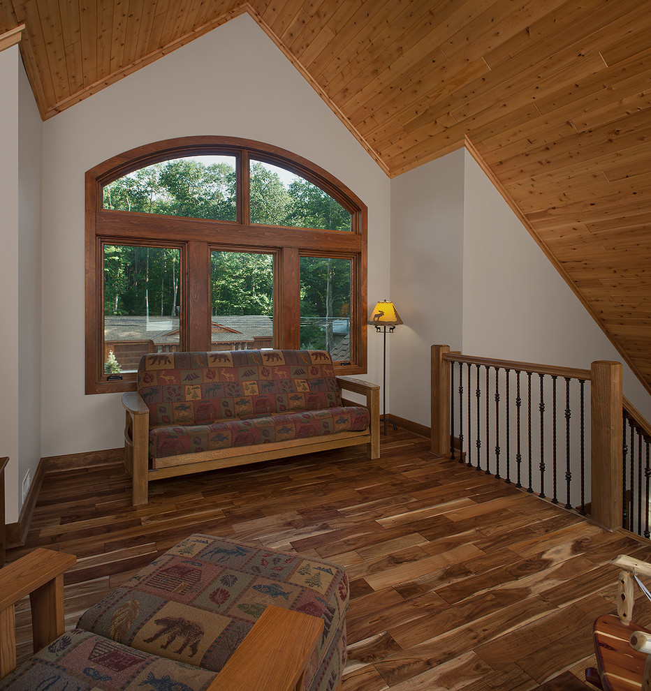 Ejemplo de sala de estar abierta rústica de tamaño medio sin chimenea con paredes beige, suelo de madera clara y televisor colgado en la pared