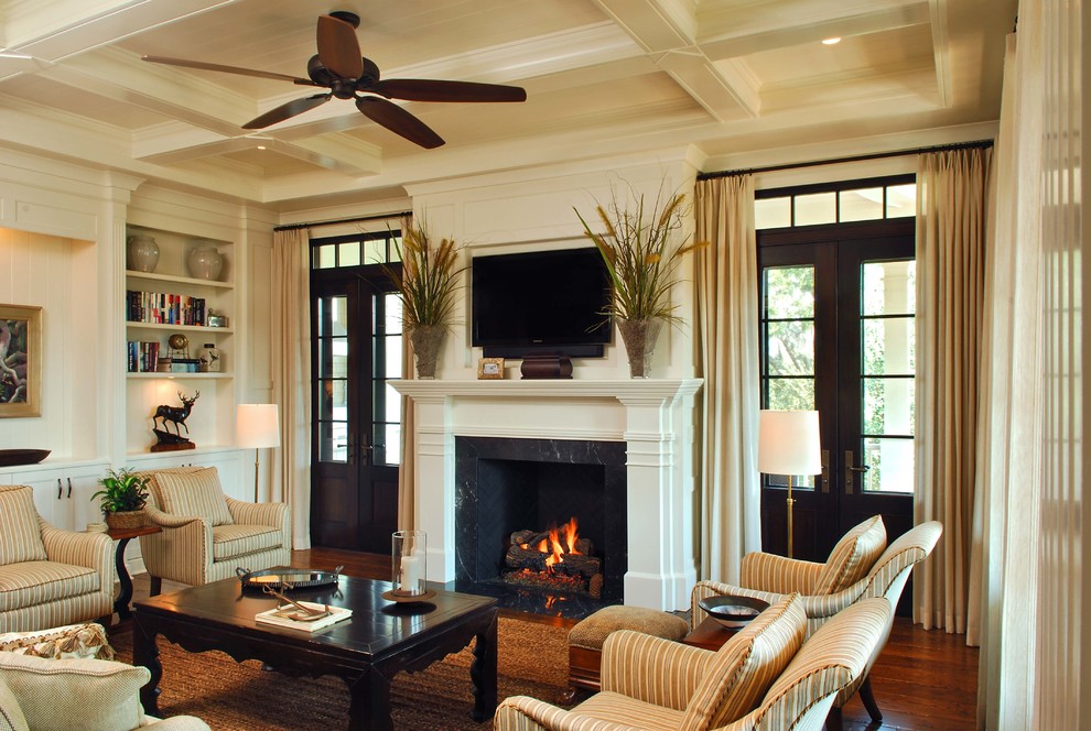 Elegant dark wood floor and brown floor family room photo in Charleston with beige walls, a standard fireplace and a wall-mounted tv
