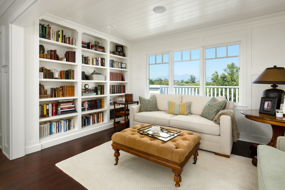 Diseño de sala de estar con biblioteca cerrada clásica pequeña sin chimenea y televisor con paredes blancas, suelo de madera oscura y suelo marrón
